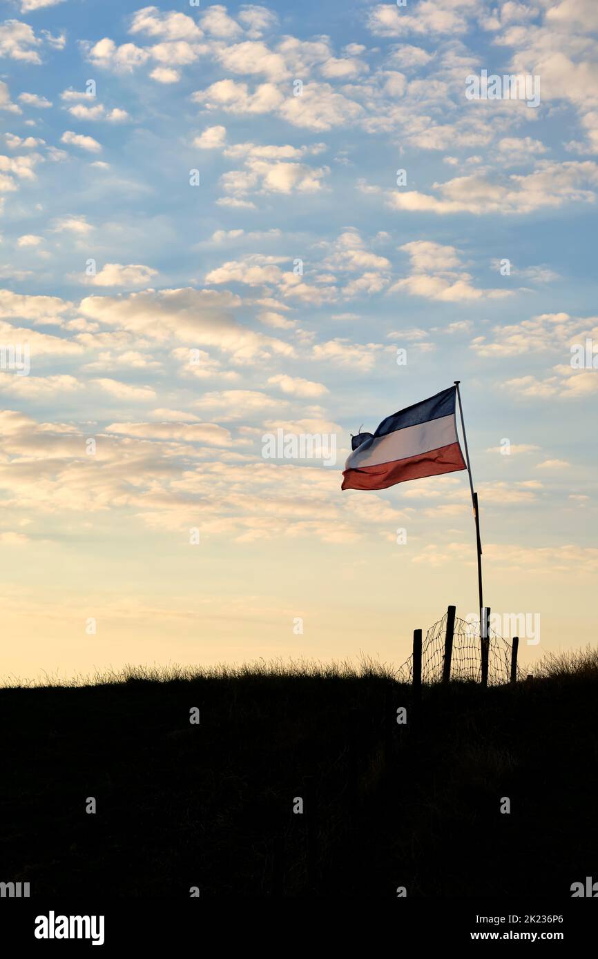 Drapeau bleu et blanc rouge néerlandais à l'envers sur une digue au coucher du soleil aux pays-Bas. Les agriculteurs des pays-Bas protestent. Banque D'Images