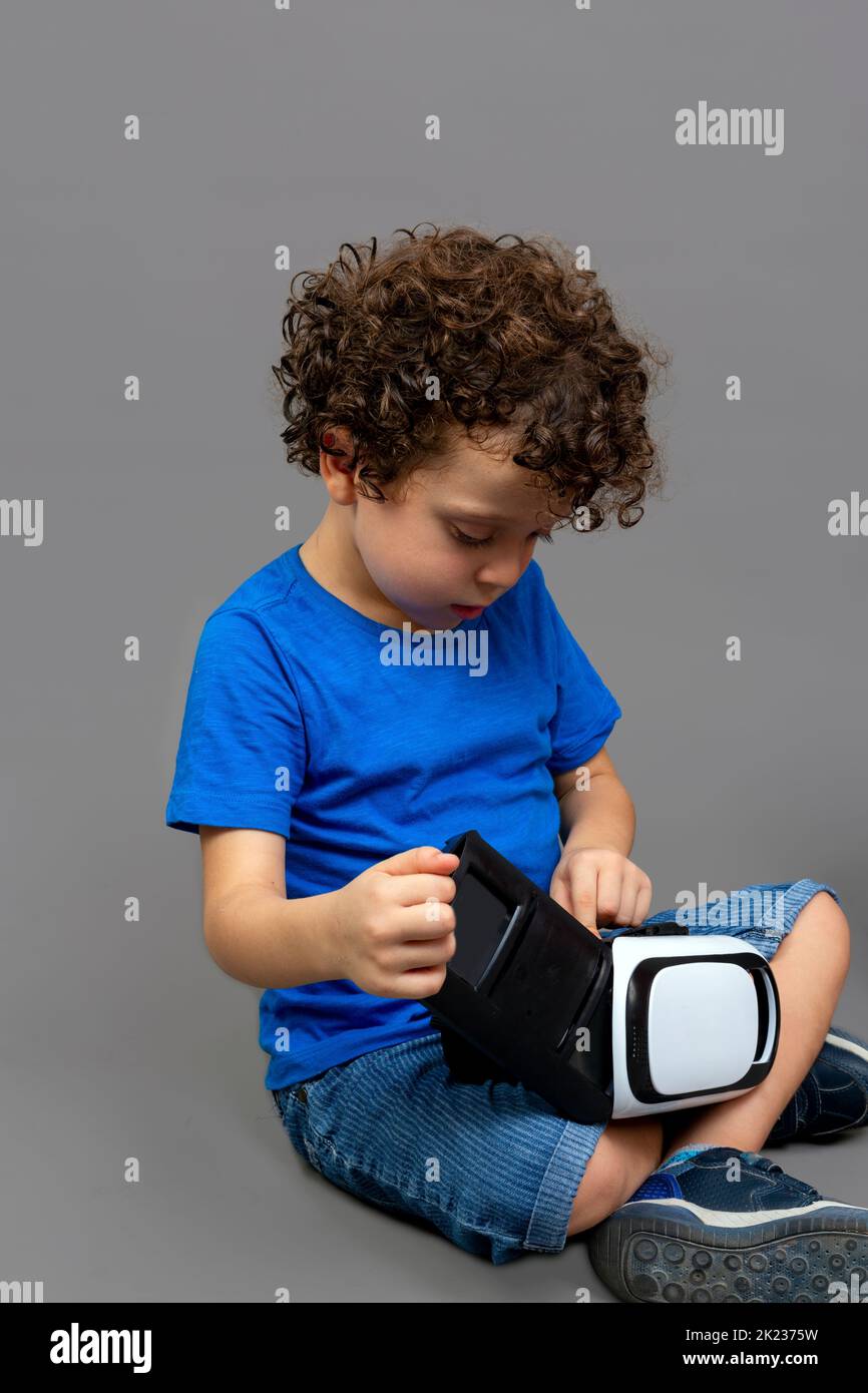 enfant avec des lunettes de réalité virtuelle dans ses mains regardant curieusement comment ils fonctionnent Banque D'Images