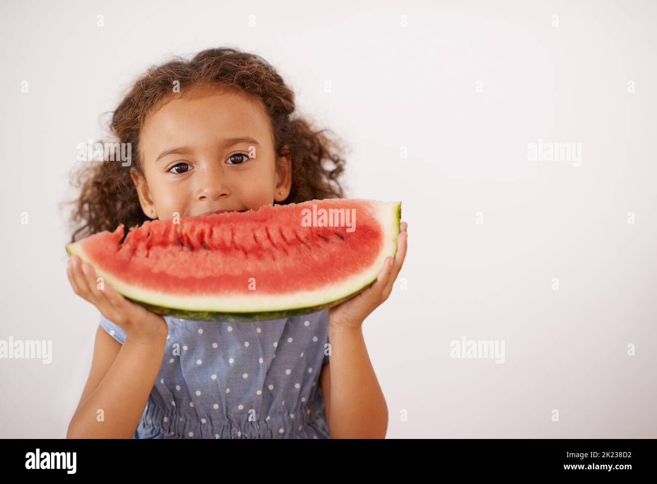 MMMM..gooooood. Une petite fille mignonne mangeant de la pastèque isolée sur le gris Banque D'Images