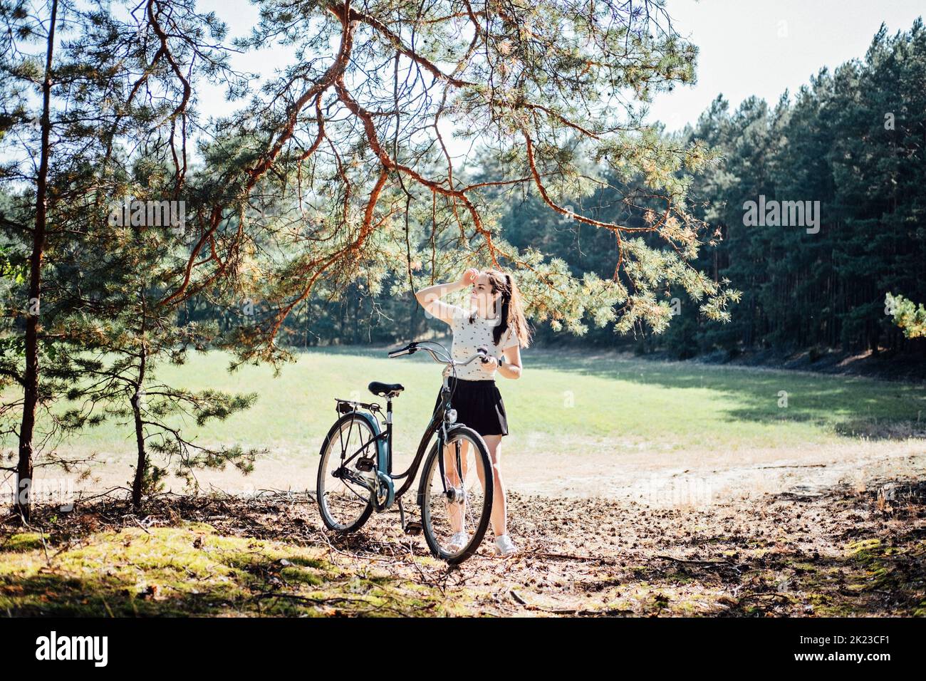 Les bienfaits du cyclisme sur la santé mentale réduisent l'anxiété. Cyclisme en forêt. Sentiers forestiers Bycycle. Femme seule à vélo dans la forêt de pins par beau temps. Banque D'Images