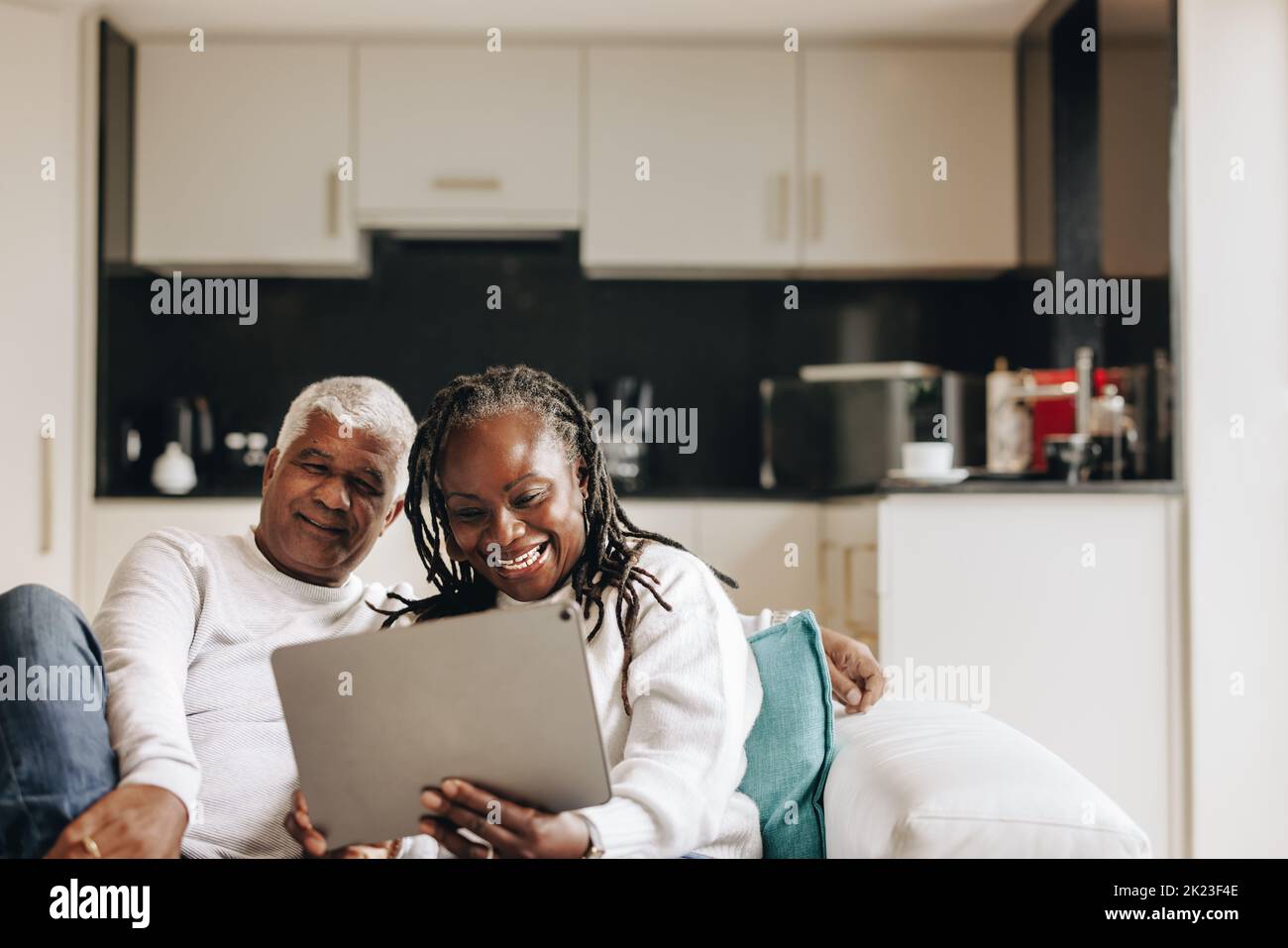 Couple senior souriant avec joie lors d'un appel vidéo sur une tablette numérique. Couple senior insouciant communiquant en ligne avec leurs proches. Maturité Banque D'Images