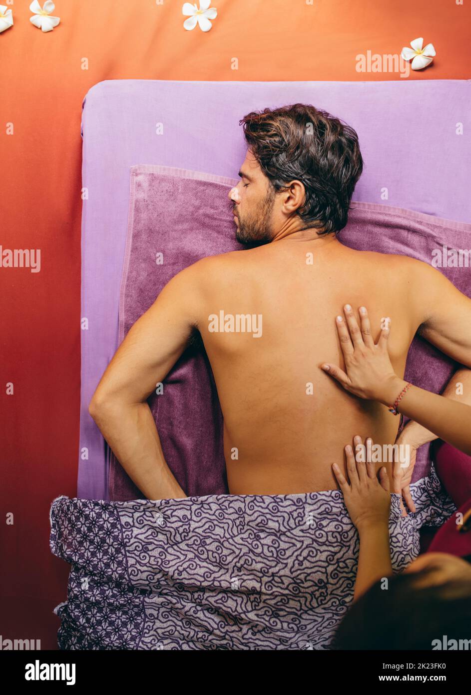 Vue de dessus d'un jeune homme allongé sur une table de massage recevant un massage du dos au spa de jour. Banque D'Images