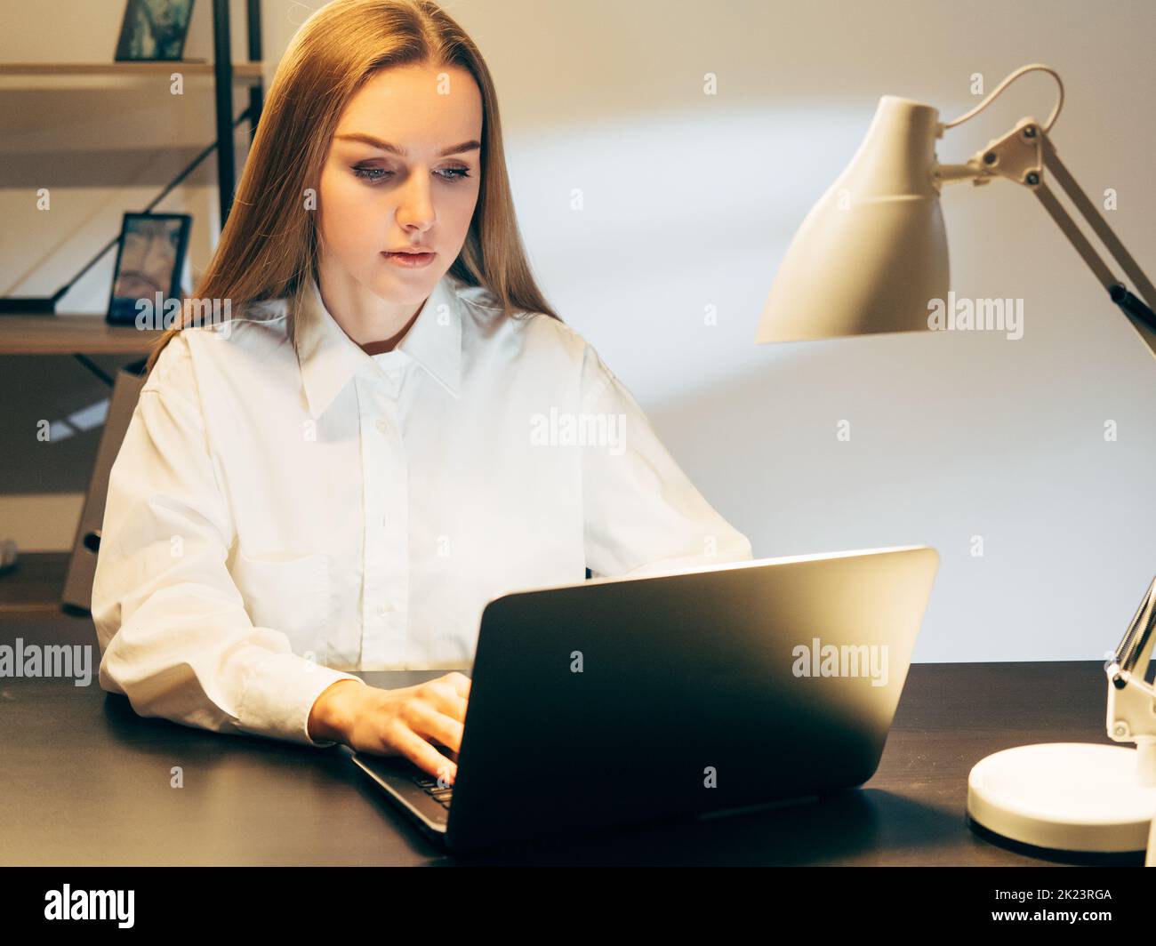 Travailler à domicile. Verrouillez vos activités. Femme travaillant sur un ordinateur portable dans un espace de travail sombre Banque D'Images
