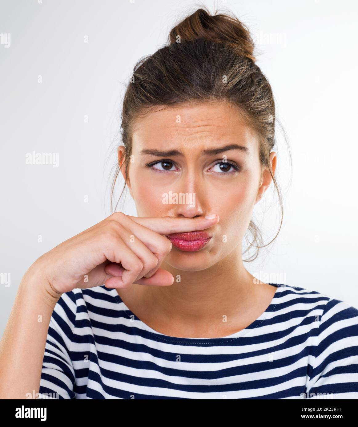 Le maître du déguisement. Une belle jeune femme utilisant son doigt pour faire une moustache. Banque D'Images