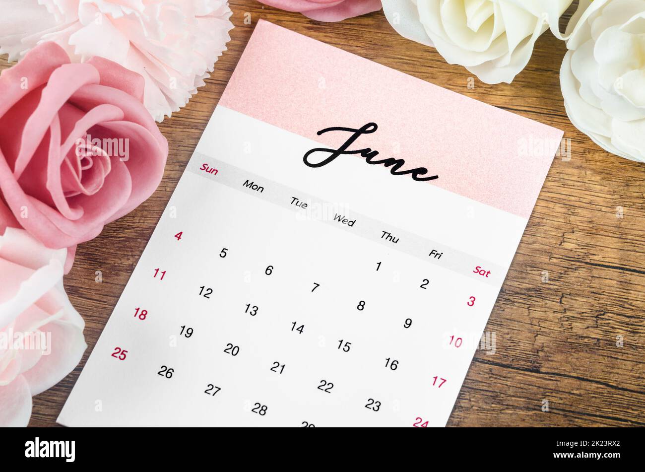 June 2023 Monthly calendar for 2023 year with pink rose on wooden background. Banque D'Images