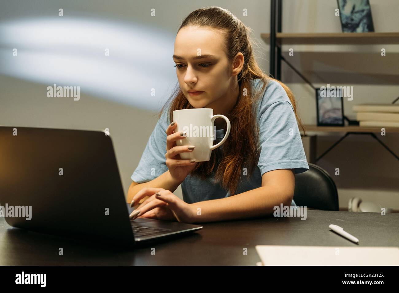 Travailler à domicile. Pause café. Verrouillez vos activités. Femme détendue travaillant sur un ordinateur portable dactylographiant dans le bureau buvant de la tasse Banque D'Images