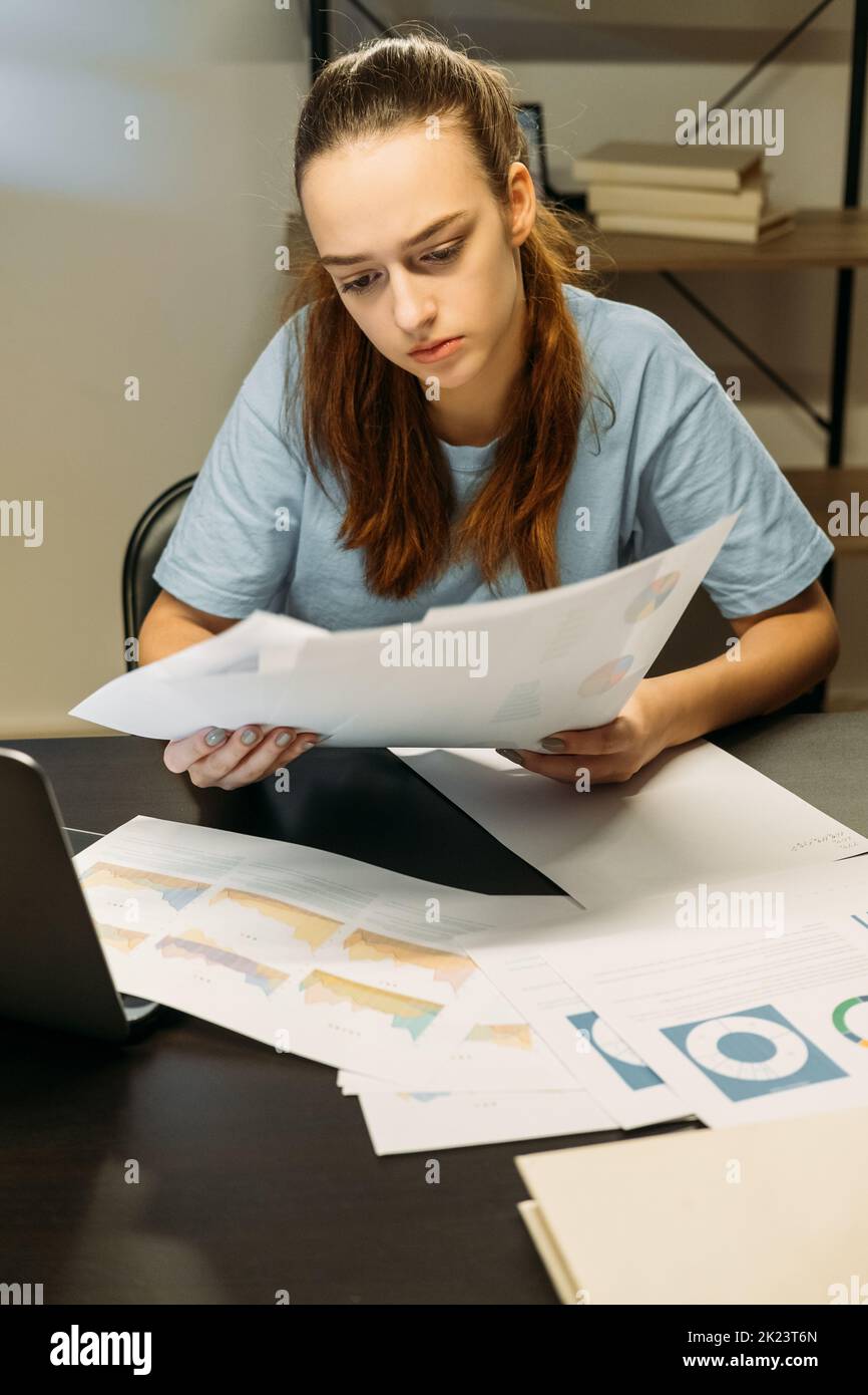 Travailler à domicile. Documentation commerciale. Femme travaillant sur un ordinateur portable dans un espace de travail sombre Banque D'Images