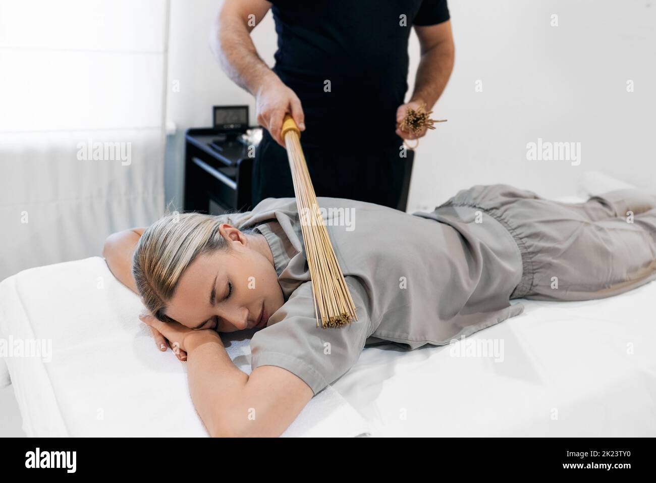 Masseuse faisant un massage avec des balais de bambou à la belle femme. Massage thérapeutique avec bâtonnets de bambou Banque D'Images