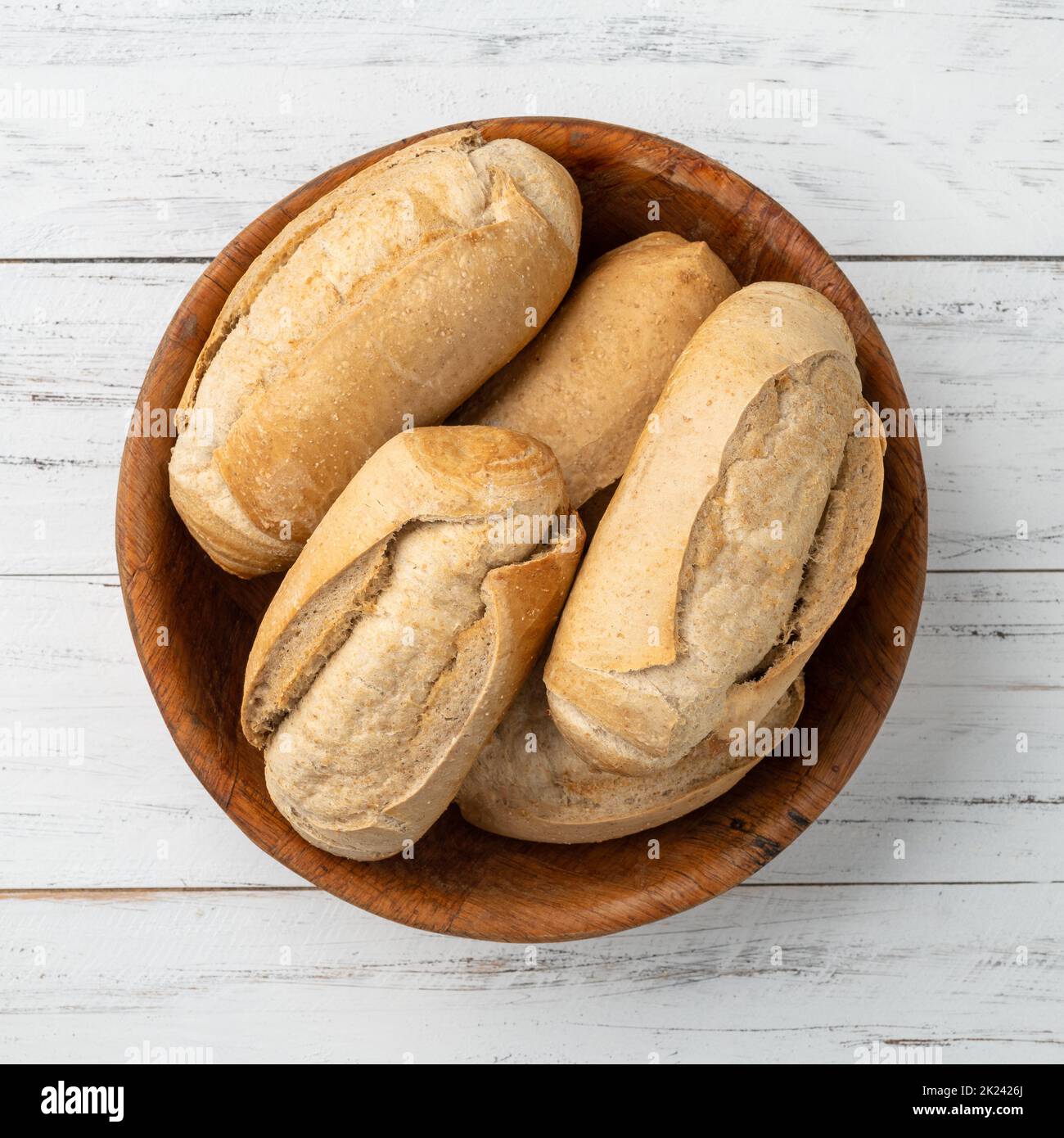 Pain français à grains entiers, pain salé ou pistolet dans un bol sur table en bois. Banque D'Images