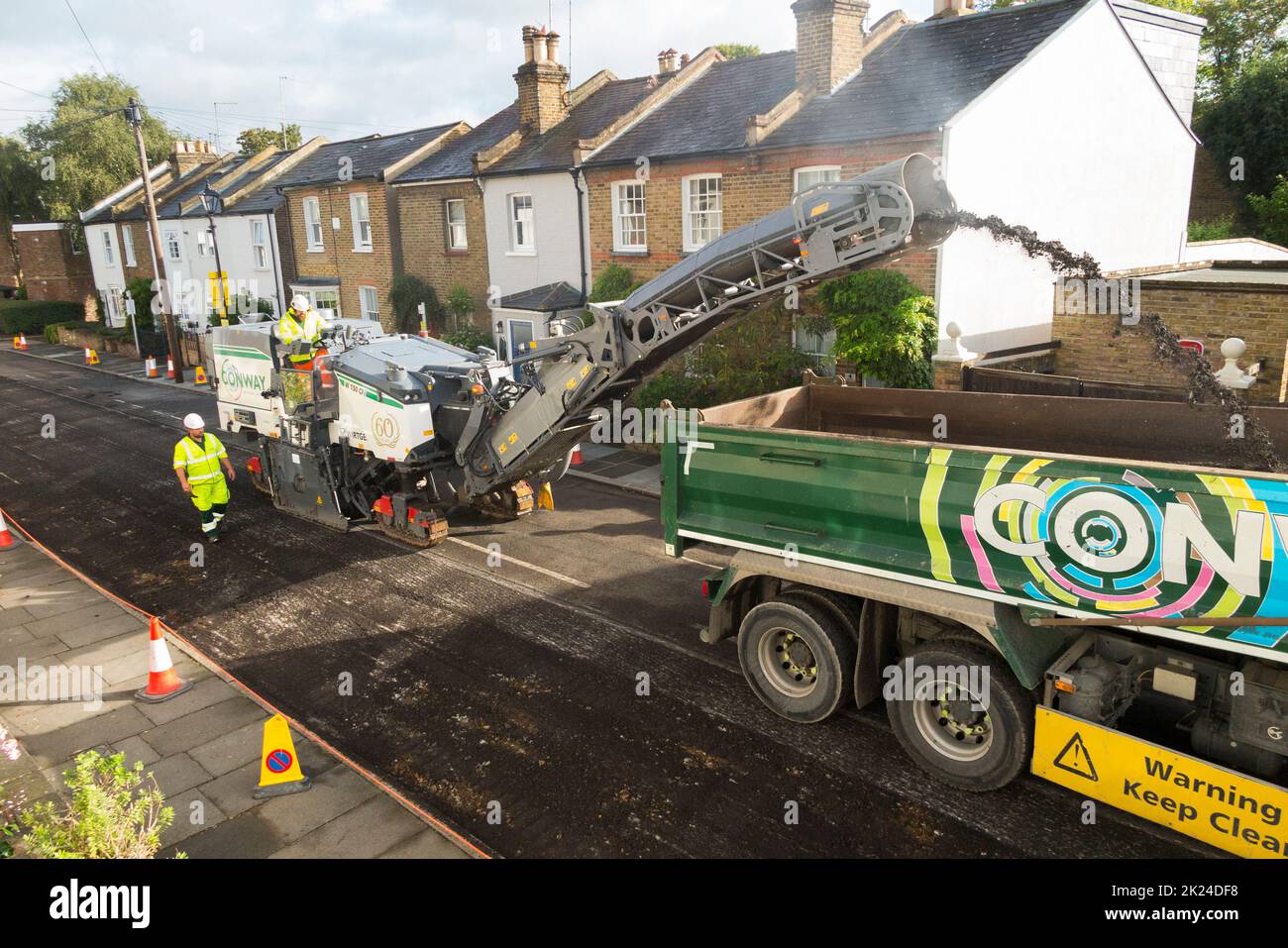 Enlèvement mécanisé de l'ancienne surface de la route avant le resurfaçage d'une rue résidentielle à Twickenham, Grand Londres, Royaume-Uni. Il sera resurfacé avec du tarmac après l'élimination de l'asphalte usé et cassis. (132) Banque D'Images