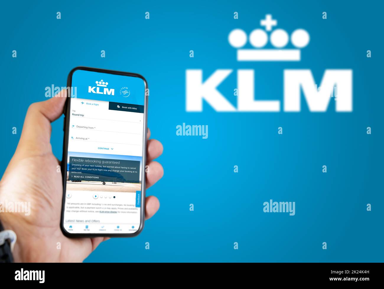 Amsterdam, NED, octobre 2021 : main tenant un téléphone avec l'application de réservation de vol KLM Airlines. Logo KLM Airlines flou sur fond bleu. Booki Banque D'Images