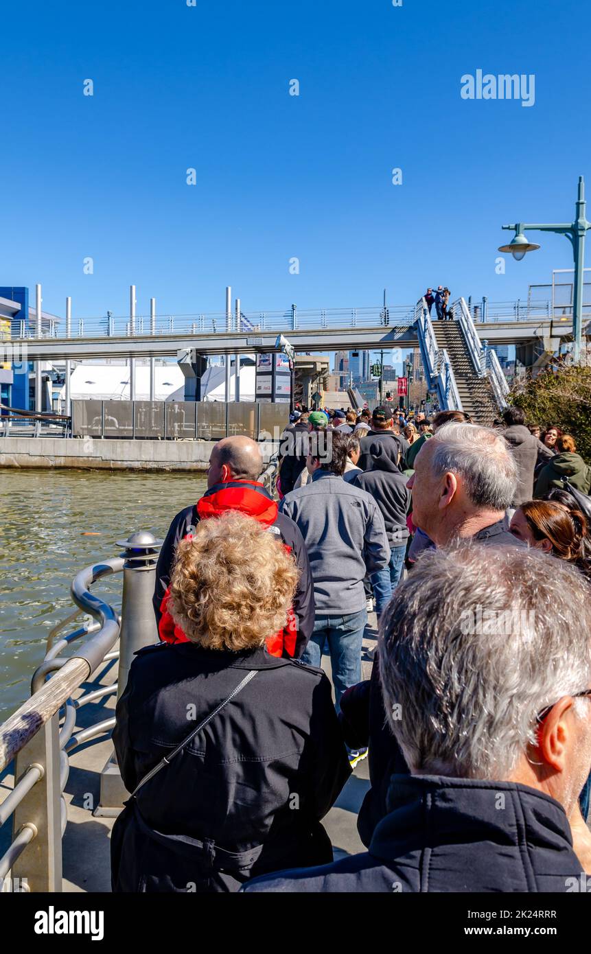 Les gens, les touristes qui attendent en file d'attente devant l'entrée du musée Intrepid Sea-Air-Space, New York City pendant la journée d'hiver ensoleillée avec ciel clair, verti Banque D'Images