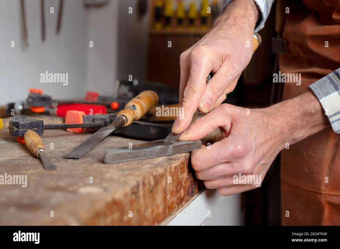 Menuisier aiguisage d'un burin. Procédé de travail du bois avec des outils à main dans un atelier de menuiserie. Concept de sculpture sur bois. Photographie de haute qualité. Banque D'Images