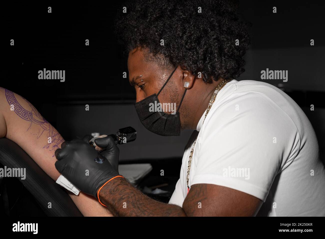 L'artiste professionnel américain de tatouage d'Afrique fait un tatouage sur le bras de client. Photographie de haute qualité. Banque D'Images