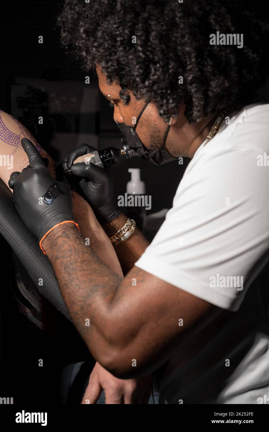 L'artiste professionnel américain de tatouage d'Afrique fait un tatouage sur le bras de client. Photographie de haute qualité. Banque D'Images