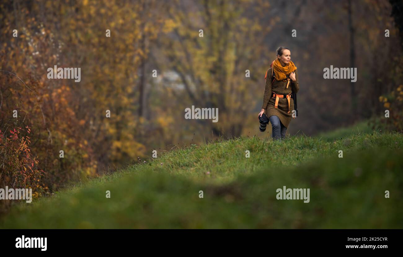 Jolie femme photographe à prendre des photos en plein air, sur une belle journée d'automne - DOF peu profond, couleur tonique libre Banque D'Images