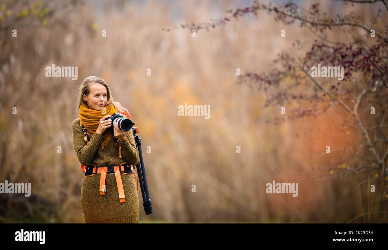 Jolie femme photographe à prendre des photos en plein air, sur une belle journée d'automne - DOF peu profond, couleur tonique libre Banque D'Images