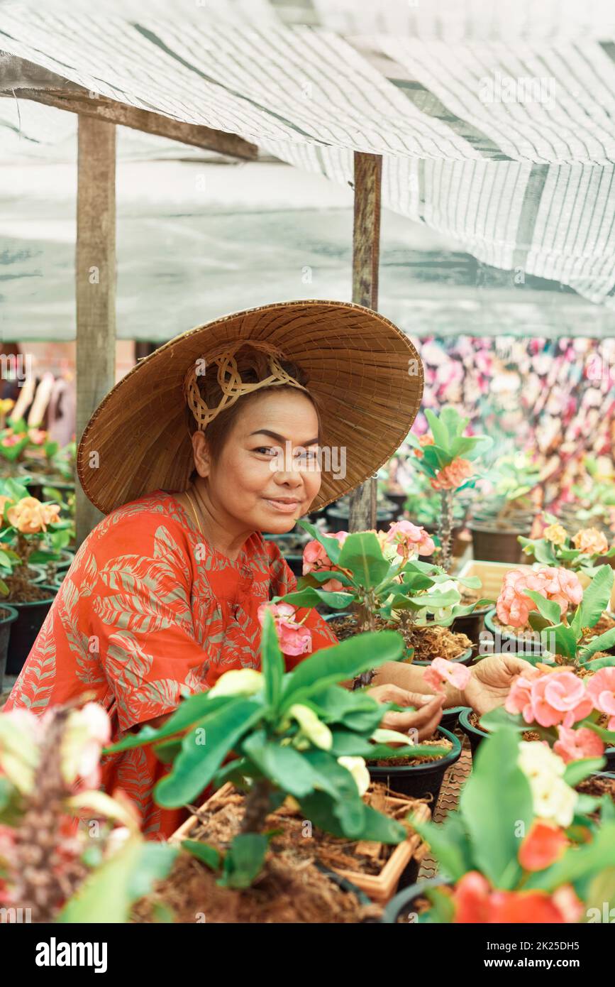 Bonne femme asiatique avec chapeau de paille vietnamien empotant des fleurs dans son jardin Banque D'Images
