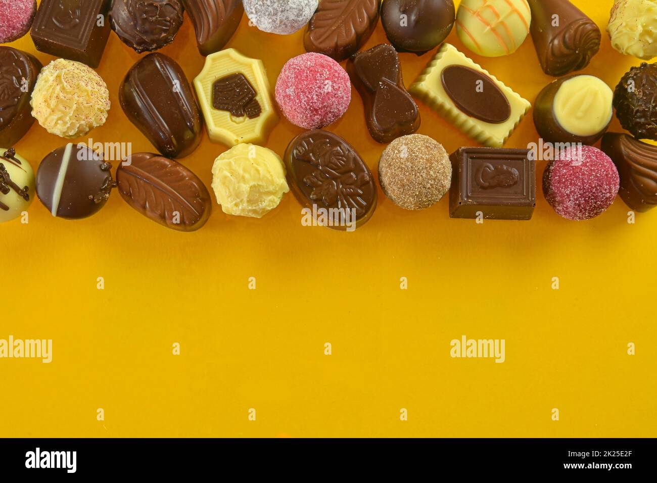 Biscuits au chocolat et pralines pour un événement de vacances sur fond jaune avec grand espace de copie. Pose à plat Banque D'Images