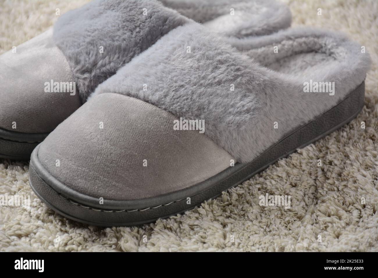Une femme chaude chaussons sur tapis gris.Pantoufles confortables Banque D'Images