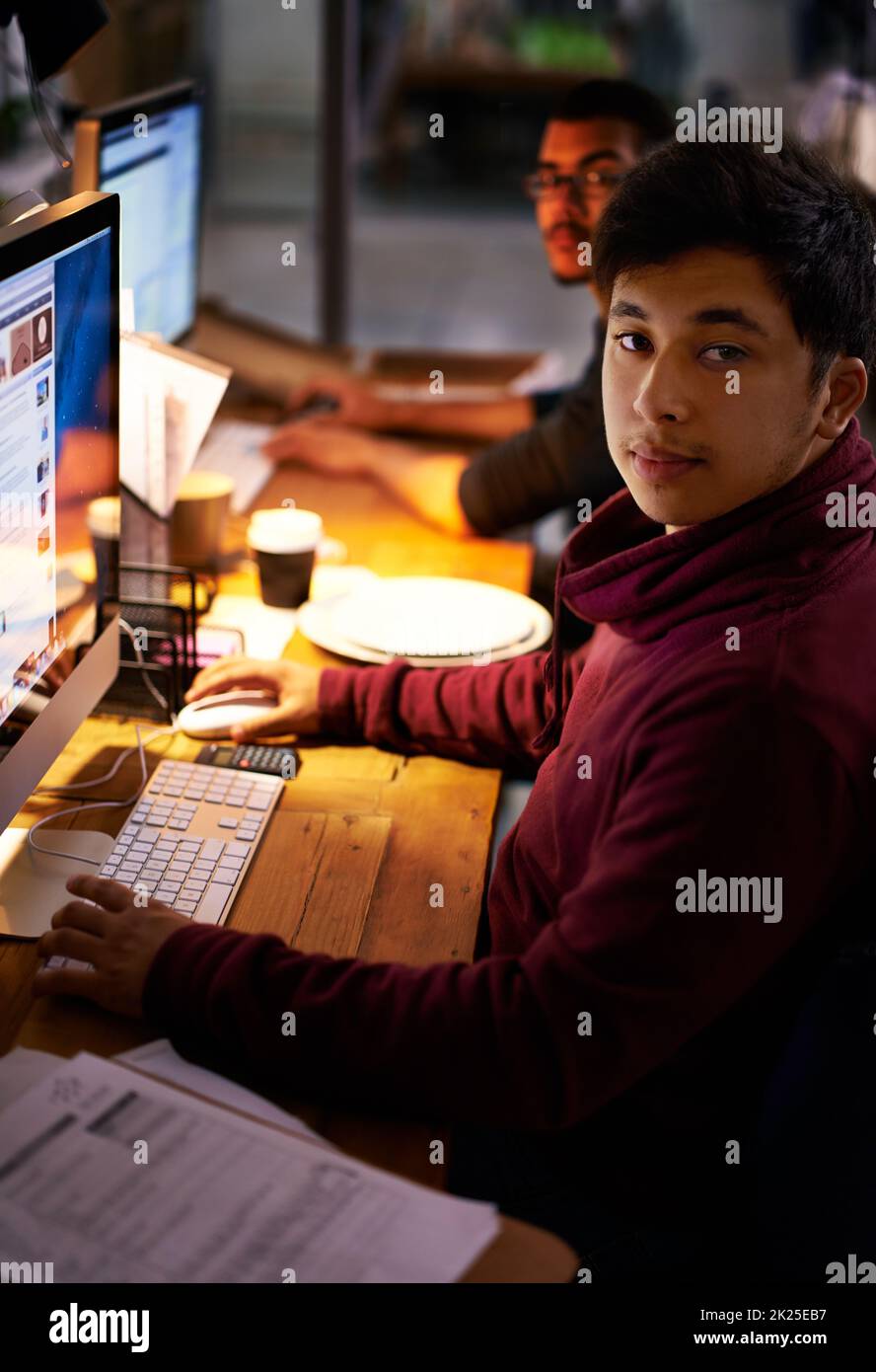 Faire le travail. Un groupe de jeunes collègues travaillant dans un bureau mal éclairé Banque D'Images