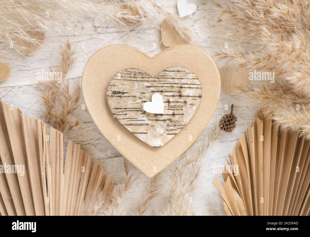 Saint-Valentin en forme de coeur présent près des coeurs, des feuilles de palmier séchées et de l'herbe de pampass Banque D'Images