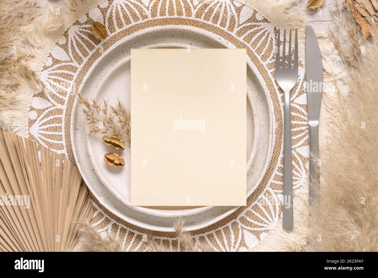 Table de mariage de boho avec carte vierge sur l'assiette près de l'herbe de pampas Banque D'Images