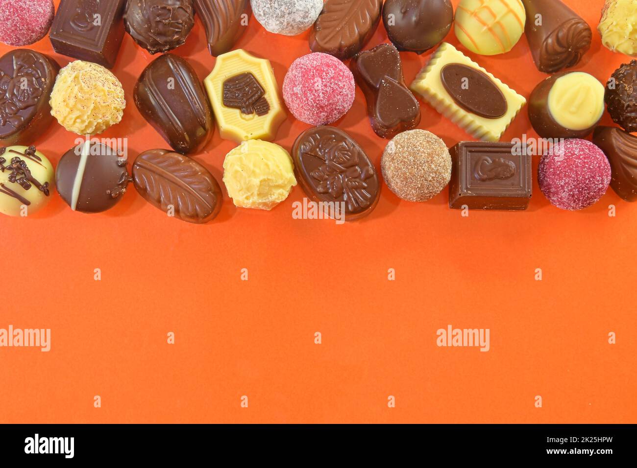 Cadre de pralines en chocolat vue du dessus des images de stock. Bonbons au chocolat sur fond orange. Cadre chocolat vue de dessus. Arrière-plan de pralines de chocolat avec espace de copie pour le texte. Bordure de différentes friandises Banque D'Images