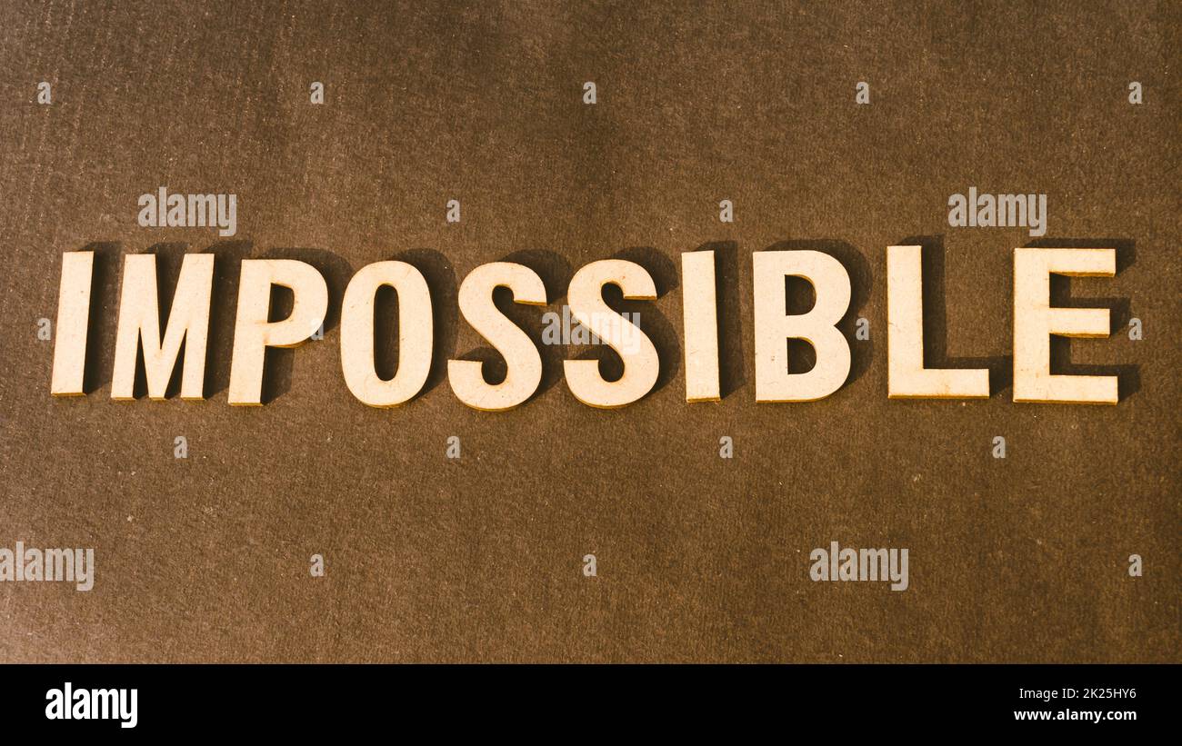 Le mot impossible écrit avec un timbre en bois brun Alphabet sur fond Vintage. Banque D'Images