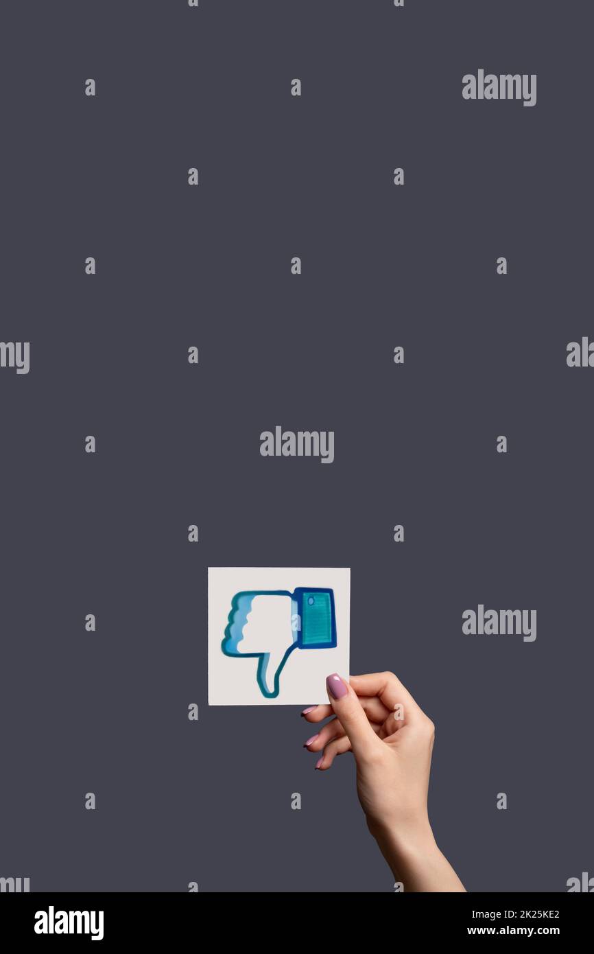 Kharkiv, Ukraine - 05 juin 2020: Contrairement à ICON. Rétroaction négative. Main d'abonné femelle montrant le signe de pouce vers le bas isolé sur l'espace de copie violet foncé ba Banque D'Images