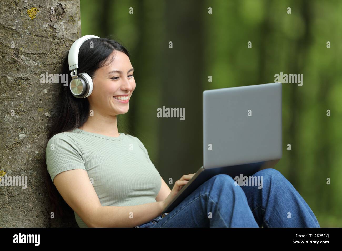 Bonne femme asiatique regardant les médias sur un ordinateur portable dans un parc Banque D'Images