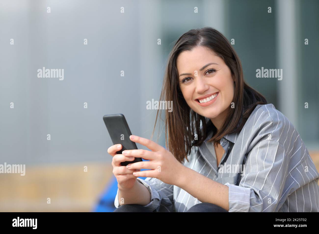 Un étudiant heureux tenant le téléphone vous regarde Banque D'Images