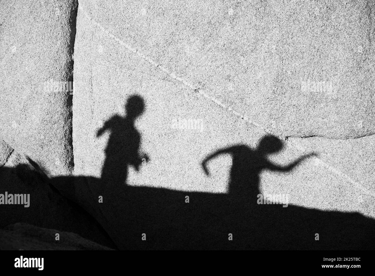 Enfants jouant avec l'ombre à un rocher dans le parc national de Joshua Tree Banque D'Images