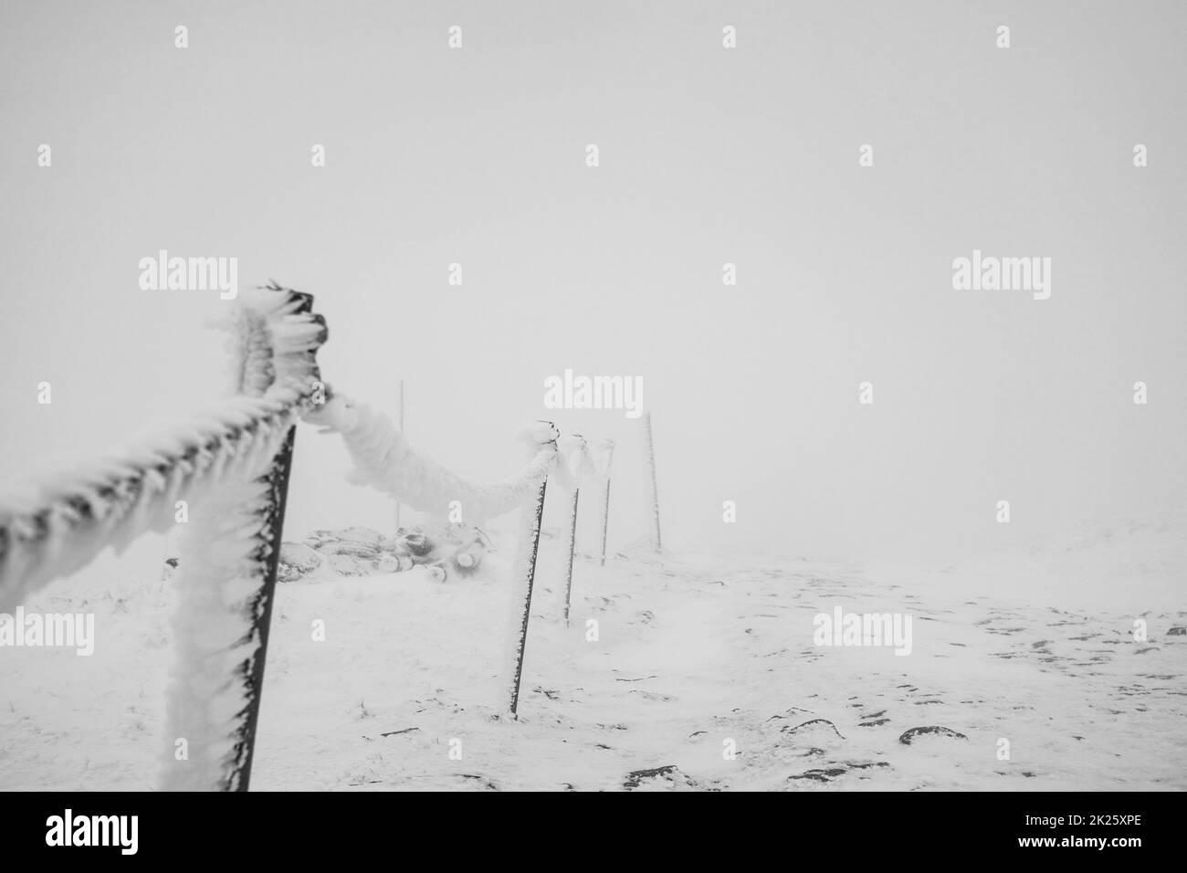 Clôture en chaîne recouverte de glace et de neige sur une section dangereuse du sentier dans les montagnes. Banque D'Images