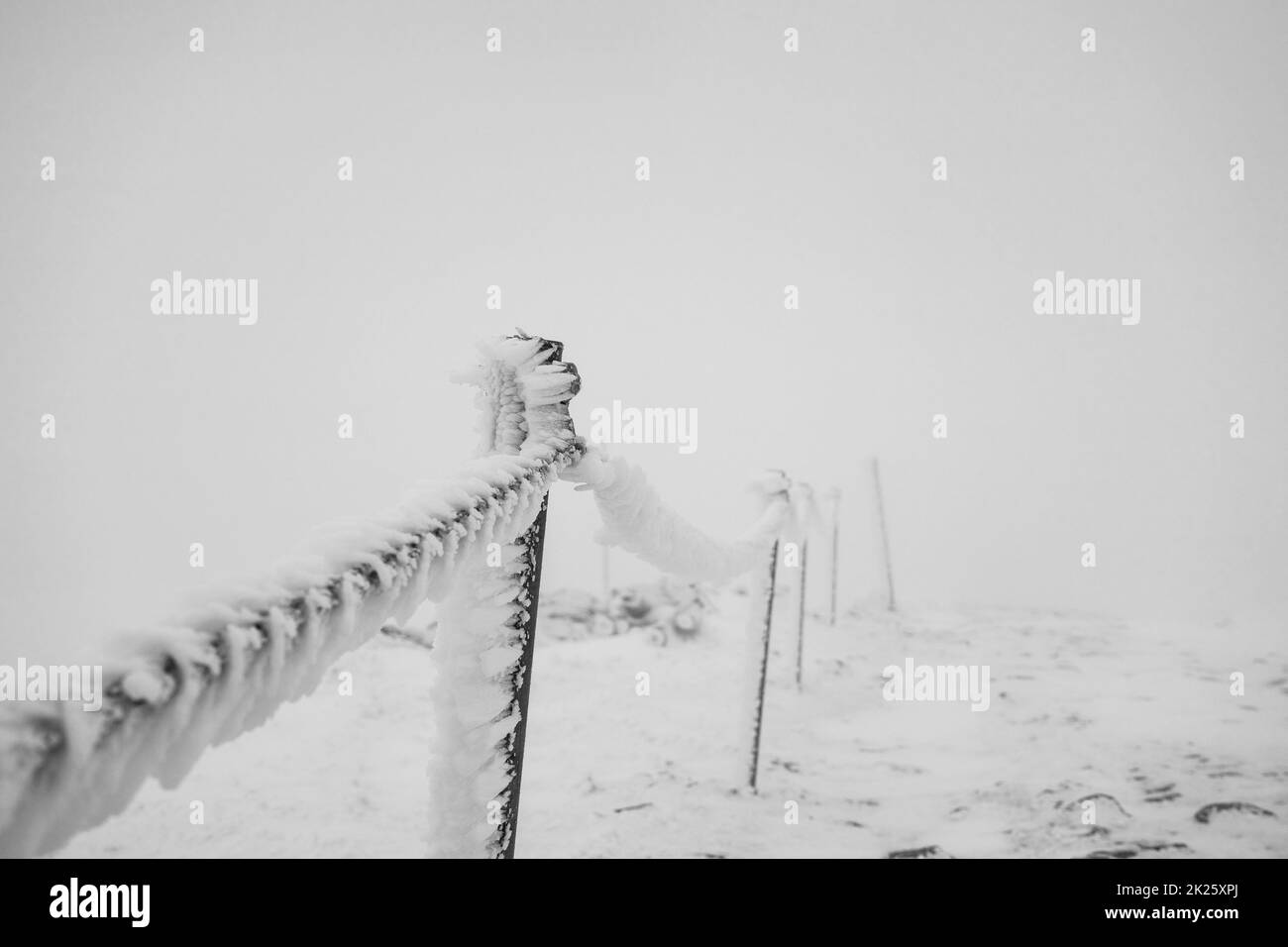 Clôture en chaîne recouverte de glace et de neige sur une section dangereuse du sentier dans les montagnes. Banque D'Images