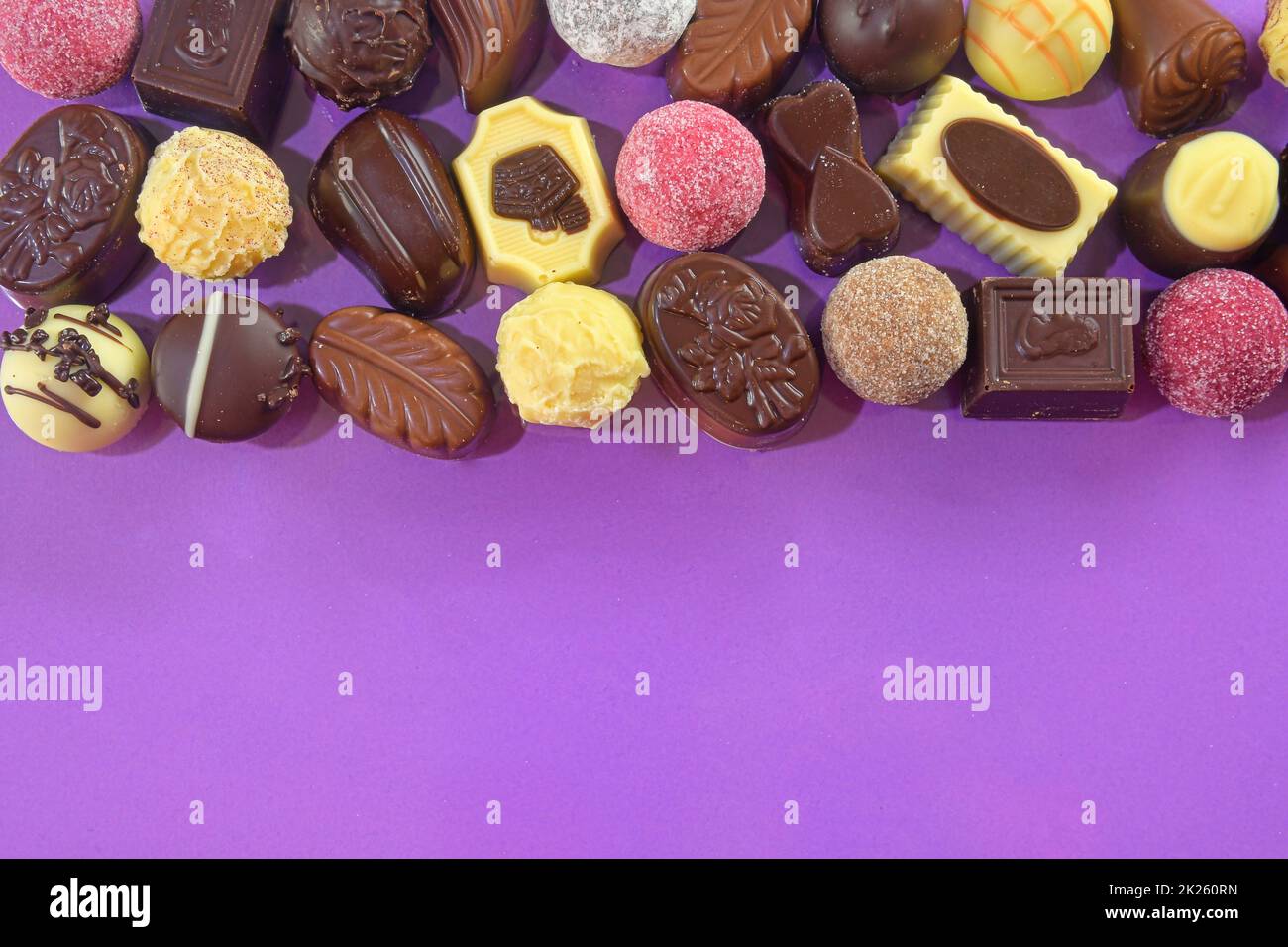 Cadre de pralines en chocolat vue du dessus des images de stock. Bonbons au chocolat sur fond lilas. Cadre chocolat vue de dessus. Arrière-plan de pralines de chocolat avec espace de copie pour le texte. Bordure de différentes friandises Banque D'Images