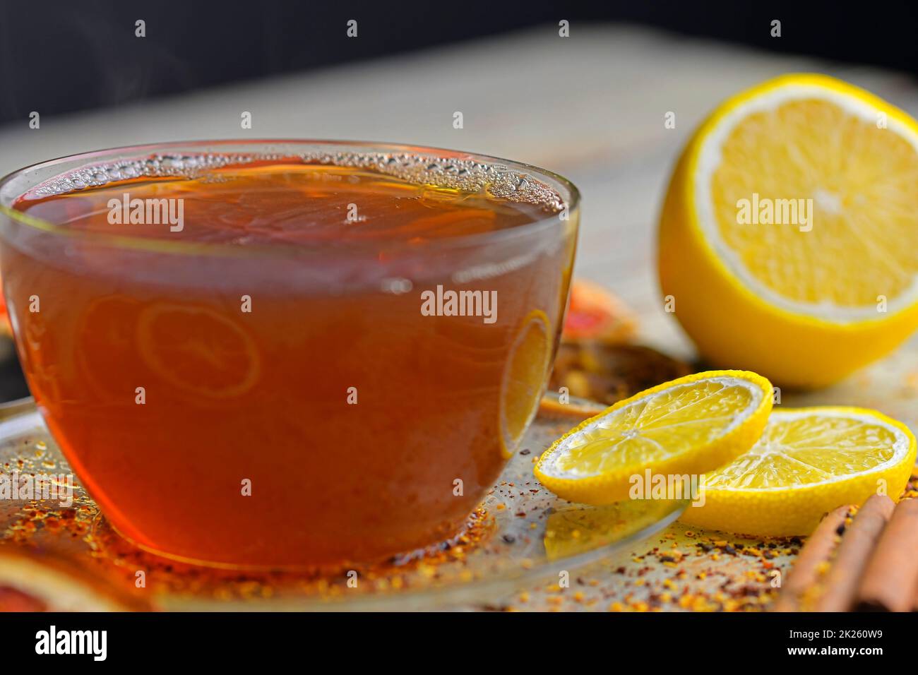 Tasse de thé en verre avec bâtonnets de cannelle sur fond de table en bois. Bâtonnets de cannelle, anis étoilé, citron et fruits secs. Arrière-plan noir. Image macro. Concept STILL Life. Banque D'Images