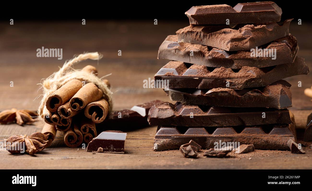 morceaux cassés de chocolat noir, bâtonnets de cannelle et anis étoilé sur une table en bois brun Banque D'Images
