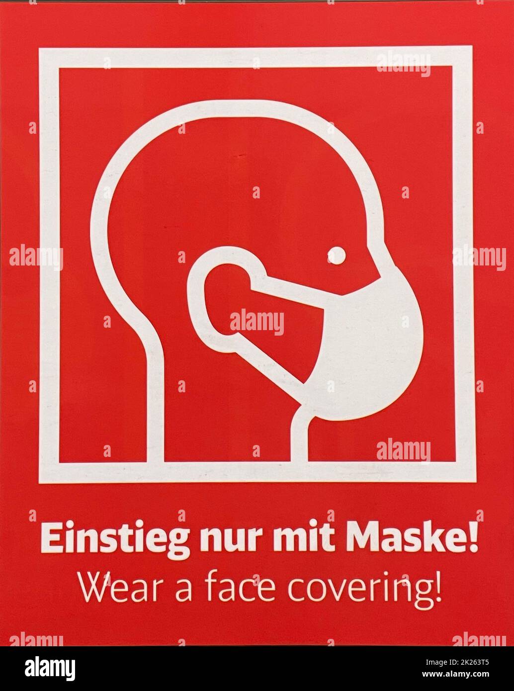 Marqueur de guidage « Wear a face cover » (Einstieg nur mit Maske!) En raison d'une pandémie de coronavirus, lettres blanches sur fond rouge - transports publics en allemand et en anglais Banque D'Images