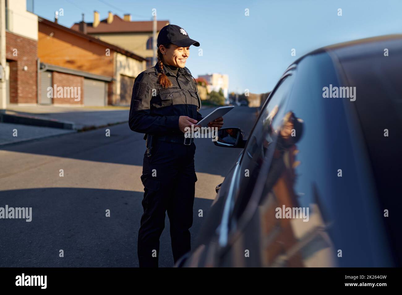 Jeune policier avec tablette debout près de la voiture Banque D'Images