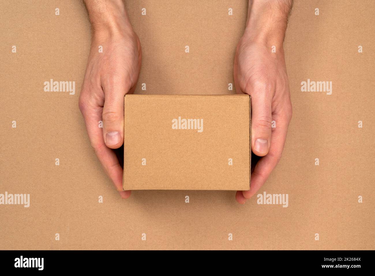 Mains avec une petite boîte en carton pour l'emballage et la livraison Banque D'Images