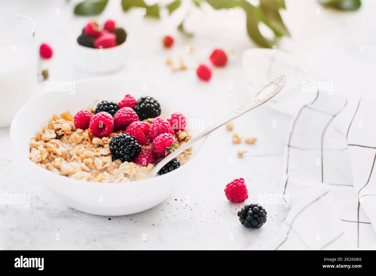 Bol petit déjeuner avec granola, muesli, framboise, mûre sur table grise Banque D'Images