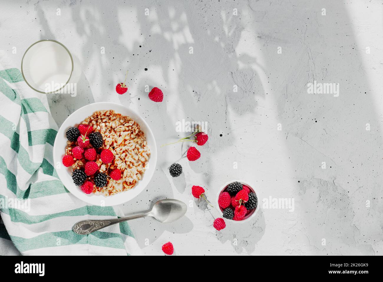 Bol petit déjeuner avec granola, muesli, framboise, mûre sur table grise Banque D'Images