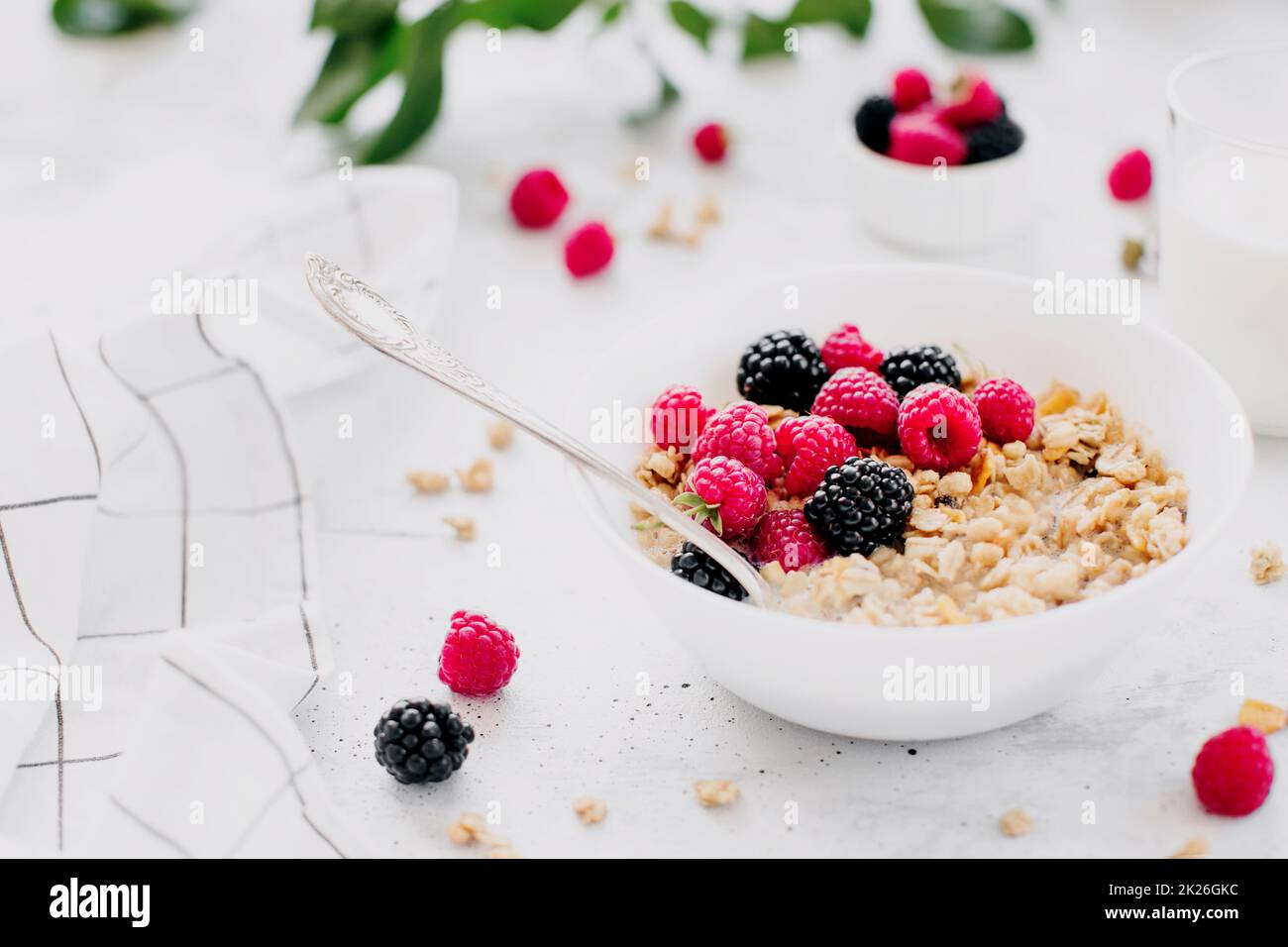 Bol petit déjeuner avec granola, muesli, framboise, mûre sur table grise Banque D'Images