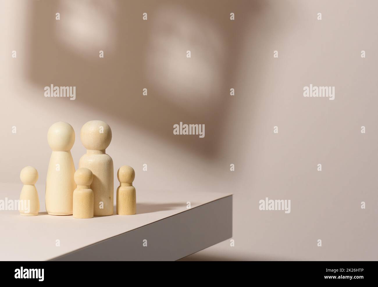 figurines en bois d'une famille sur fond d'ombre sous la forme d'une maison.Arrière-plan beige.Maison rêves, hypothèque Banque D'Images