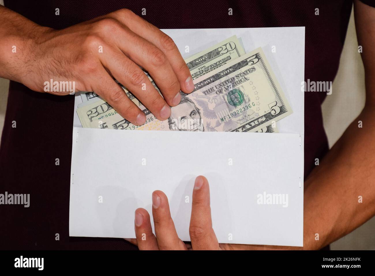 Argent dans enveloppe blanche dans les mains d'un homme. Dollars, un wad de dollars. Banque D'Images