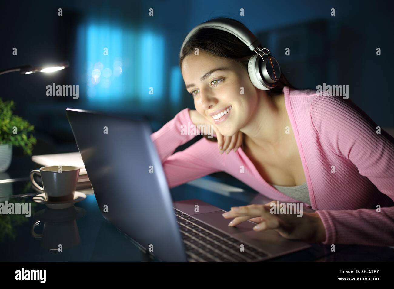 Bonne femme regardant des médias avec un ordinateur portable et un casque Banque D'Images
