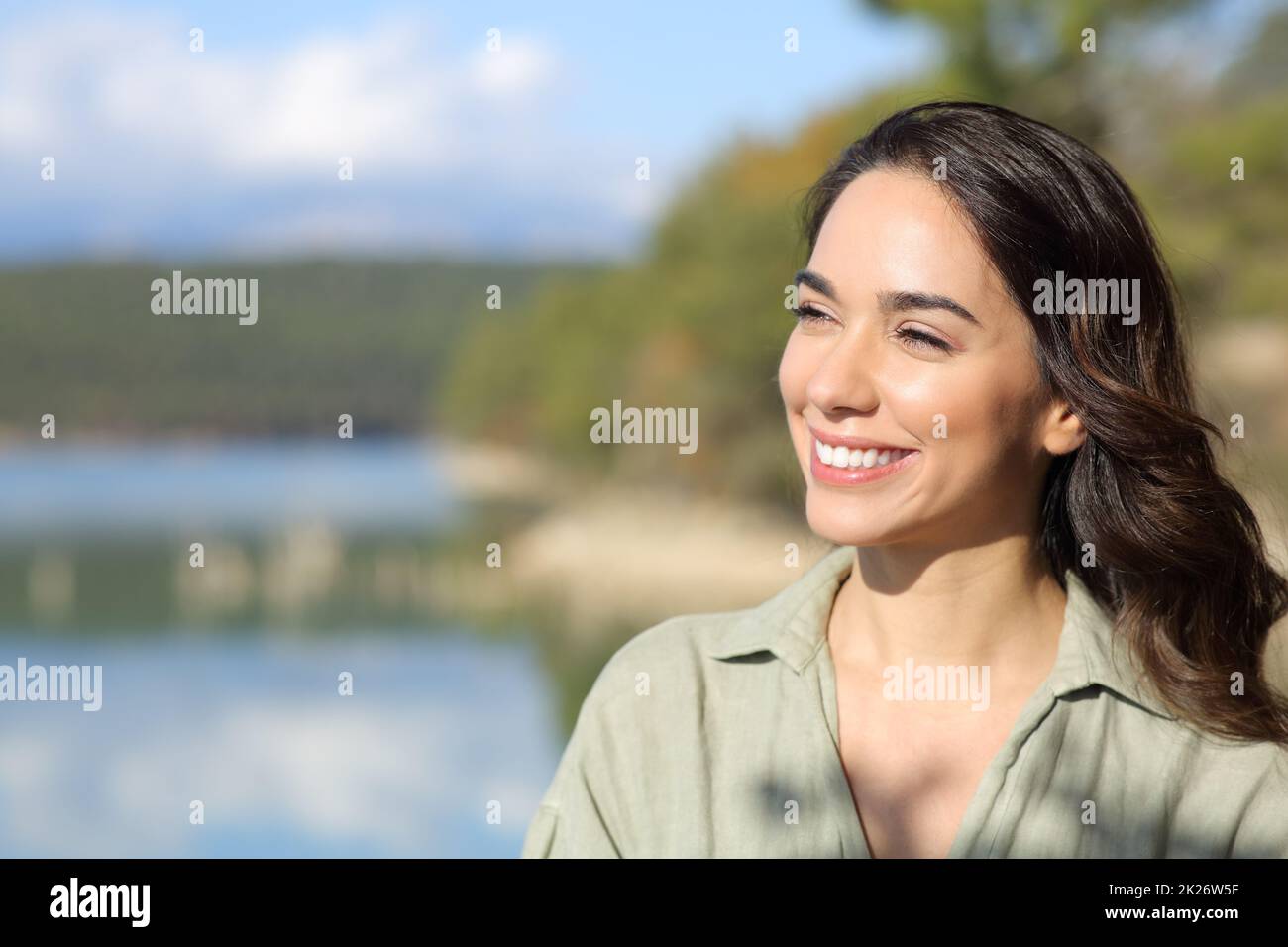 Bonne femme souriante regardant loin dans un lac Banque D'Images