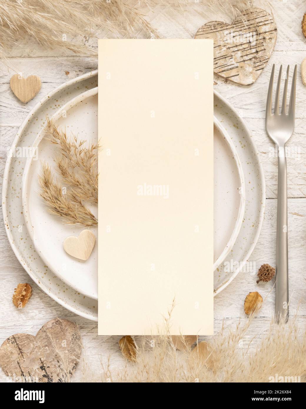 Table de mariage avec carte de menu vierge près des plantes séchées et des coeurs, maquette Banque D'Images