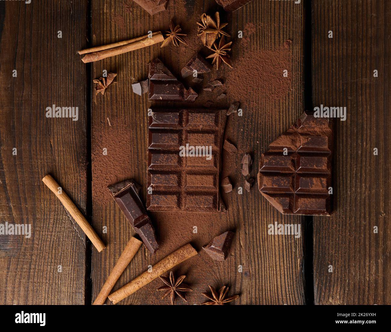 morceaux de chocolat noir cassés, bâtonnets de cannelle et anis étoilé sur une table en bois marron, vue du dessus Banque D'Images